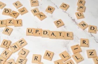 Wooden Scrabble tiles arranged to spell 'Update' among scattered letters on a marble background.
