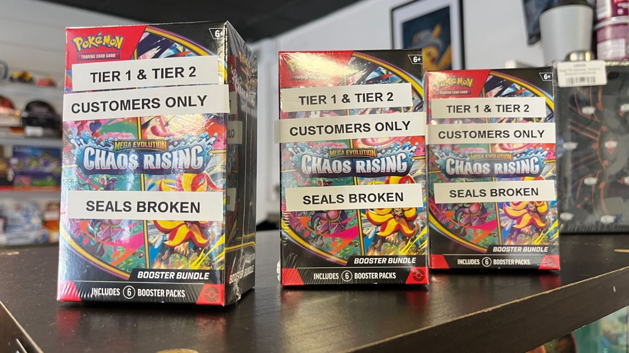 Three boxes of Chaos Rising Pokemon cards stand on a shop counter.
