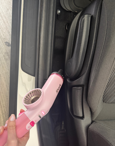 Leah using Shark BlastBoss to blow debris off of car floor under driver's seat