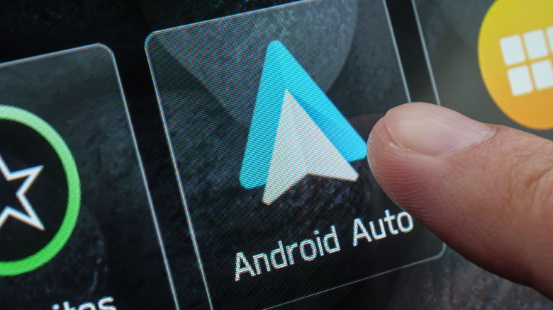 Close-up of a driver selecting Android Auto app on the infotainment system.