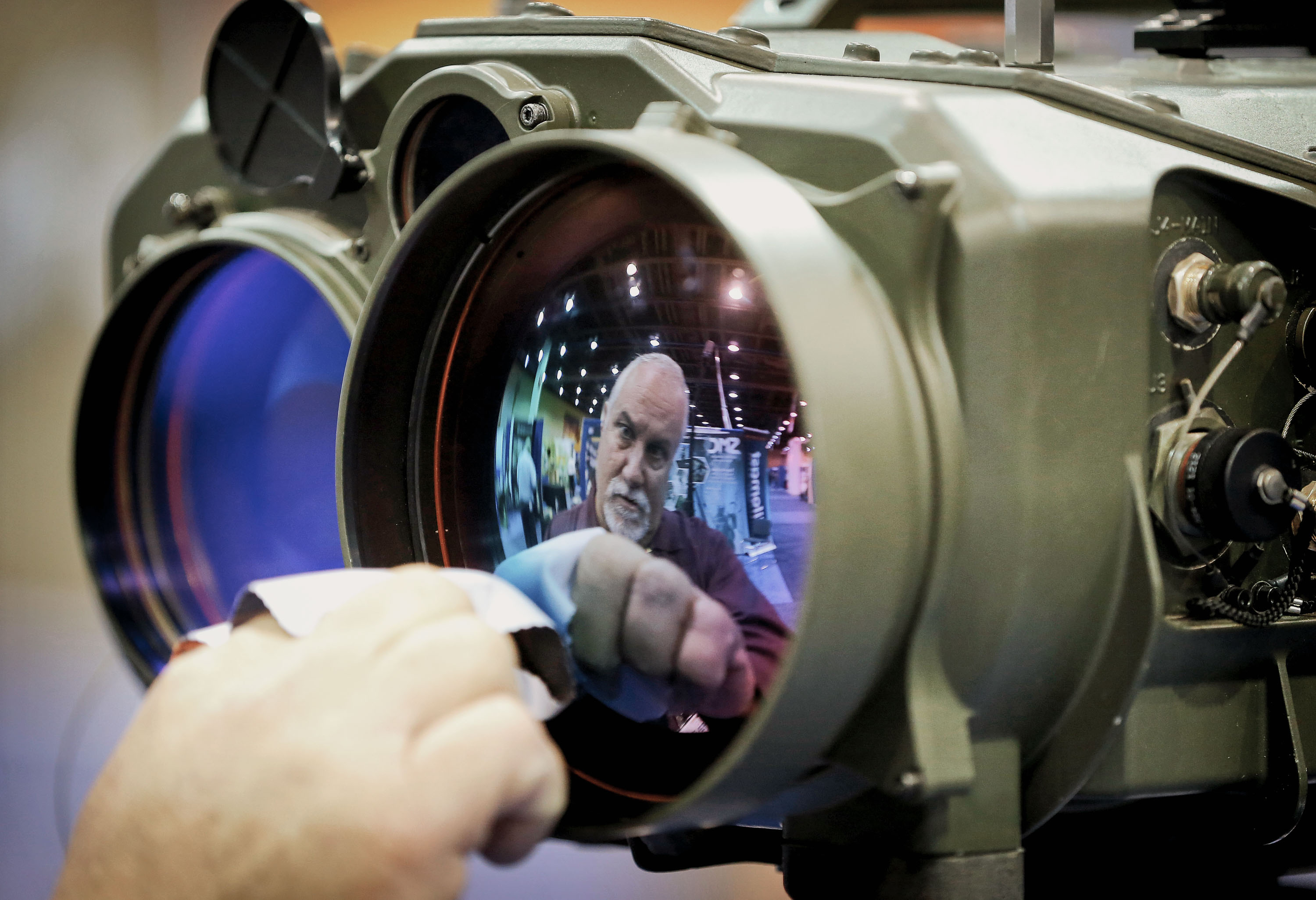 Gary Wagner, of Elbit Systems of America, cleans the lens of a long range thermal imaging targeting system at the 8th annual Border Security Expo, Tuesday, March 18, 2014 in Phoenix.