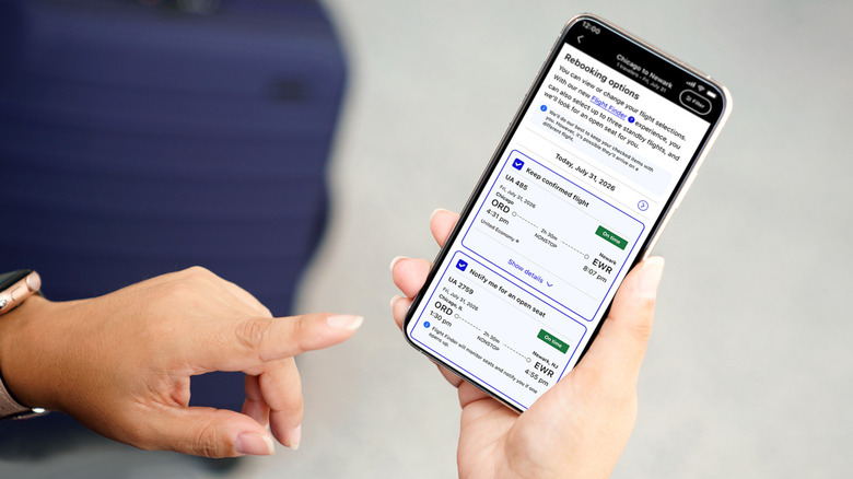 A person holding a phone showing the United app